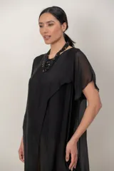 Maxi blusón negro de seda con diseño asimétrico en picos y mangas cortas fluidas.