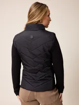 Campera acolchada con frente y espalda en tejido técnico, combinada con mangas y laterales de tejido liso. Presenta cuello alto, cierre frontal completo y bolsillos laterales. Incluye un pequeño detalle bordado en el pecho.