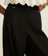 Pantalón de sastrería corte wide leg, de tiro alto con cintura doble y detalle de remaches metálicos en la parte frontal.