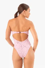 Traje de baño enterizo color rosa con textura arrugada, corte bandeau, herrajes dorados y copas extraíbles.