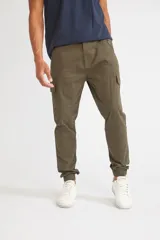 Pantalón cargo de corte slim, color verde oliva, con bolsillos laterales tipo cargo, cierre frontal con botón y puños elásticos en los tobillos.