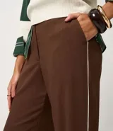 Pantalón de sastre color marrón, de corte recto, con rayas verticales finas y piping contrastante en los laterales. Confeccionado en viscosa certificada.