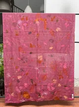 Mantel rectangular de lino color rosa con estampado de hojas y flores en tonos naranja, marrón y blanco.