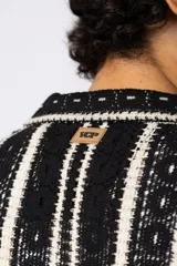 Camisa de manga corta tejida al crochet con diseño de rayas verticales negras sobre una base color crudo. Presenta cuello solapa y cierre frontal con botones.