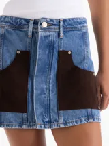 Minifalda de denim azul con calce clásico, lavado especial y grandes bolsillos delanteros de gamuza marrón en contraste, con remaches metálicos.