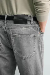 Jeans de denim de algodón en color negro con efecto lavado, corte amplio y silueta curva tipo barrel fit con pinzas en las rodillas. Presenta diseño clásico de cinco bolsillos y cierre frontal con cremallera y botón metálico.