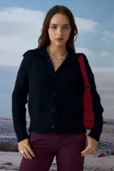 Cardigan negro de punto con cuello tipo polo y cierre frontal de botones. Presenta un diseño de textura acanalada y corte ajustado.