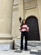Buzo deportivo de corte holgado con diseño de rayas horizontales anchas en color marrón y rosado. Presenta cuello tipo polo con cierre frontal de botones y mangas largas con puños ajustados.