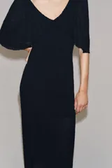 Vestido largo de punto color negro, con escote en V pronunciado tanto en el delantero como en la espalda, y mangas cortas anchas con vuelo.