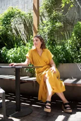 Vestido midi color amarillo mostaza, de lino y viscosa, con cuello camisero, manga corta y corte cruzado con lazo ajustable en la cintura.