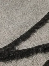 Bufanda de tejido suave y ligero, color bordó con flecos negros y beige en los extremos.