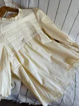 Blusa negra de manga larga con detalles de encaje y frunces en el pecho. Presenta cuello redondo con volados y puños con elástico y volado.