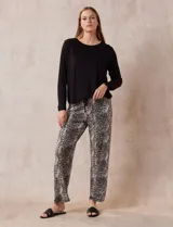 Conjunto de pijama marca René Rofé, compuesto por remera negra de manga larga con bolsillo en el pecho y pantalón largo con estampado animal print, cintura elastizada y lazo de ajuste.
