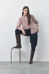 Camisa de manga larga a rayas verticales en tonos blanco y bordó, con cuello alto y detalle de volados frontales. Presenta puños con volados y un corte fluido.
