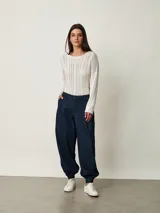 Pantalón slouchy de denim azul oscuro con pinzas en la cintura, bolsillos laterales y puños fruncidos con elástico en los tobillos.