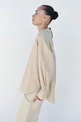 Blusa amplia confeccionada en mezcla de viscosa y lino, color beige, con cuello solapa, escote en V y manga larga.