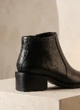 Bota corta de cuero vacuno en color bordó, con diseño combinado de cuero liso y textura de reptil. Cuenta con taco cuadrado de 5 cm, suela de caucho antideslizante y cierre lateral.