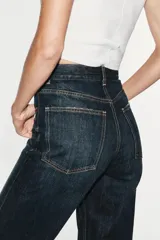Jeans de tiro alto y estilo wide leg, con diseño de cinco bolsillos, lavado oscuro con efecto desgastado, pierna ancha larga y bajo sin costuras.