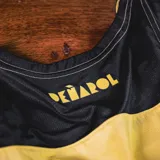 Musculosa de basquet Puma del club Pearol, modelo Home 2025. Diseo a franjas verticales amarillas y negras, con escudos del club y logo de Puma en el pecho.