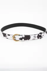 Cinto de cuero sintético con estampado de vaca en blanco y negro, hebilla metálica dorada y forro interior negro.
