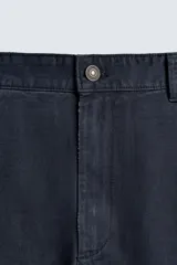 Pantalón de corte carrot fit confeccionado en tejido de algodón con estructura diagonal y efecto lavado. Presenta bolsillos frontales con bolsillo cerillero, bolsillos traseros de plastrón y cierre frontal con cremallera y botón.