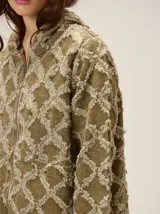 Chaqueta de algodón con diseño de textura desflecada en forma de rombos, cierre frontal con cremallera, cuello alto y puños elásticos.