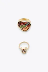 Pack de dos anillos dorados: uno con forma de corazón esmaltado con motivos florales y la palabra "LOVE" en relieve, y otro con forma de calavera de azúcar esmaltada con detalles florales rojos.