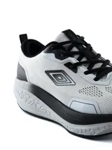 Championes deportivos Umbro modelo Belmo, color negro con suela blanca gruesa y amortiguación texturizada, diseño de malla transpirable y logo de la marca en el lateral.