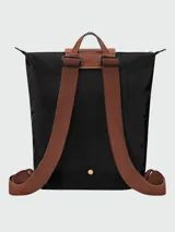 Mochila de diseño minimalista en color beige, con solapa y asa superior en cuero marrón texturizado. Cuenta con correas ajustables en color marrón y cierre principal.