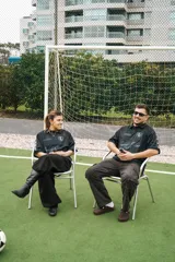 Camiseta de fútbol estilo boxy de manga corta y cuello polo, en color negro con sutiles rayas verticales. Presenta inscripciones estampadas y escudo bordado en el pecho.