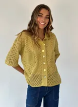 Camisa de punto calado color pistacho con hilos de lurex. Posee cuello camisero, botones frontales, mangas cortas y bolsillos delanteros.