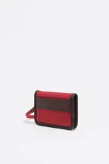 Billetera compacta de Bimba y Lola en color verde oliva, confeccionada en poliamida con detalles en piel vacuna. Presenta logo metálico en el frente y correa de muñeca extraíble.