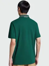 Remera polo Moncler de algodón color verde oscuro, con cuello y puños acanalados con doble raya blanca y roja. Presenta cierre de dos botones y el logo de la marca bordado en el pecho.