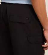 Bermuda masculina color negro, confeccionada en poliamida, con cintura elástica y cordón ajustable. Presenta bolsillos cargo laterales y es de secado rápido.