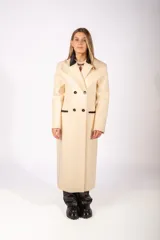 Tapado largo de paño color beige, con diseño de doble botonadura, solapas con detalle en contraste negro y bolsillos laterales con ribete negro.