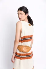 Riñonera de cuero color marrón claro con cierre superior y correa ajustable.