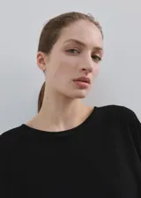 Poncho negro de diseño asimétrico, con cuello redondo y mangas amplias tipo capa.