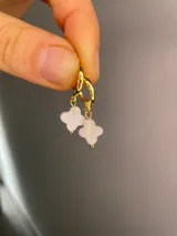 Aros tipo argolla dorados con dije colgante en forma de flor de nácar.