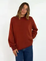 Sweater de tejido de punto en color azul marino, con cuello redondo, mangas largas con puños acanalados y ajuste holgado. Presenta un pequeño aplique decorativo en el ruedo.