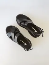 Sandalias negras de cuero con tiras cruzadas, plataforma track y hebilla lateral.