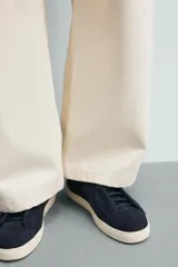 Zapatilla de piel con acabado en serraje de color gris, diseño de cordones ocultos y suela de goma en contraste de color blanco.