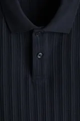 Remera polo de punto texturizado color azul marino, de manga corta, con cuello y cierre frontal parcial de botones, corte slim fit.