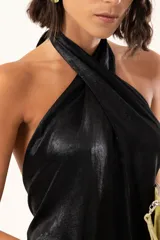 Vestido midi de satén color negro, con escote halter cruzado y ruedo terminado en flecos largos.