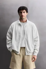 Sudadera de corte relajado con cierre frontal de cremallera, confeccionada en tejido ligero de mezcla de algodón. Presenta cuello subido, manga larga, bolsillos laterales ocultos en costura y acabados en rib.