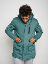 Parka larga gris con capucha, cierre frontal con cremallera y botones a presión, múltiples bolsillos y logo de Umbro en el pecho.