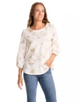 Blusa de cuello redondo con bordado floral en hilo dorado. Presenta mangas tres cuartos abullonadas con puños elásticos fruncidos y ruedo redondeado con corte asimétrico.