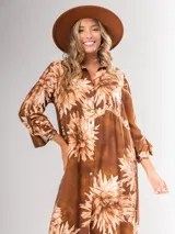 Vestido camisero largo con estampado floral en tonos rojos y negros, con cuello camisero, abotonadura frontal y mangas largas con puños abotonados.