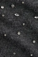 Top de punto fino color gris oscuro, de manga corta y cuello redondo. Presenta detalles de strass aplicados en la parte frontal y terminaciones acanaladas en cuello, mangas y ruedo.