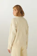 Buzo de tejido de punto industrial color marrón oscuro, con cuello medio y diseño de bloques cuadrados en relieve.