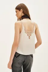 Top tipo musculosa de modal satén color crema, con detalle de encaje calado y bordados a tono en el escote delantero y en la espalda.